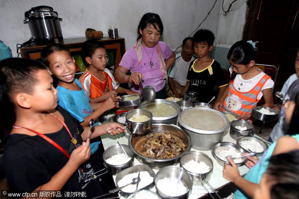 Xiong Tinghe, wife of Deng Weixing, distributes food for children living at the 'home for left-behind students' in Shitai township of Yingde city, South China's Guangdong province. Photo taken on Sept 19, 2010.