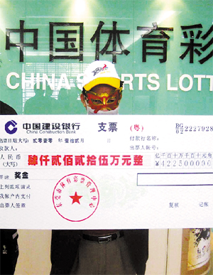 The 42-million yuan jackpot winner dressed in a disguise poses for a photo while holding his check, in Dongguan, Dec 31, 2010. [Photo/Guangzhou Daily] 