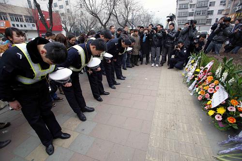 Police officers and residents in Tai&apos;an city, Shandong province, on Wednesday bow to salute the police officers who died chasing the two gunmen on Jan. 4, 2011 in Shandong province. [Xinhua]