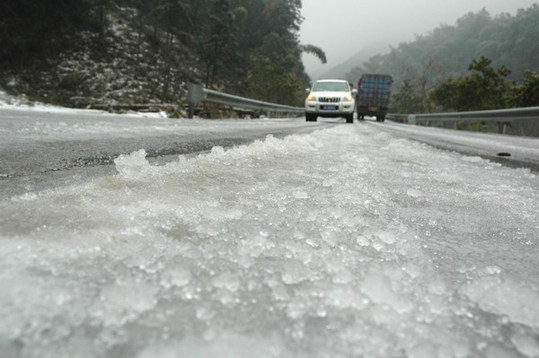 Vehicles move at snail pace along the ice-covered road in Ziyuan county, Southwest China's Guangxi Zhuang autonomous region, Jan 5, 2011. Freezing rains since Jan 2 has iced three main roads linking Ziyuan county to outside. The local road bureau and police security bureau are taking measures to tackle the disaster. [Xinhua] 