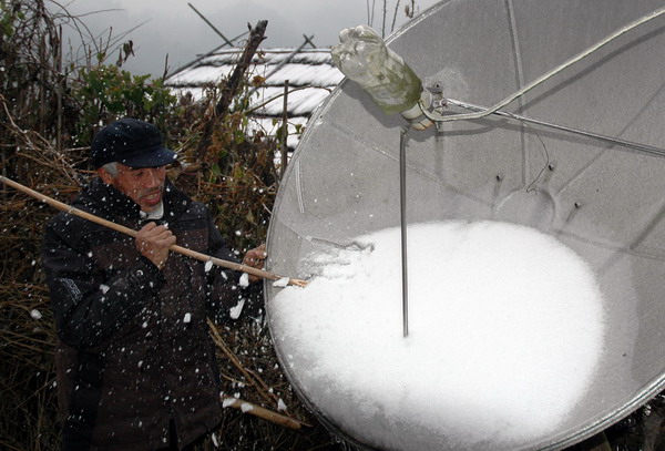 A man shovels ice on a satellite receiver in Ziyuan county, Southwest China's Guangxi Zhuang autonomous region, Jan 5, 2011. 