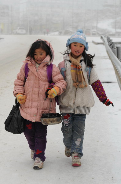 Two pupils bundled up walk to school carrying a heater in Yangliu village, Wulong county, Southwest China&apos;s Chongqing municipality, Jan 4, 2011.