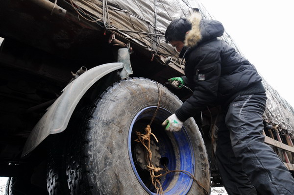 A driver sets up a tire chain to the wheels while waiting amid a traffic jam on the Huaihua section of NO 319 national highway in Hunan, Central China&apos;s Huann Jan 4, 2011.