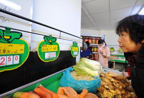 A woman looks at the price boards of vegetables at a store in Urumqi, capital of Northwest China&apos;s Xinjiang Uygur autonomous region Jan 4, 2011.