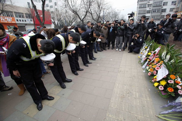 Police officers and residents in Tai'an city, Shandong province, on Wednesday bow to salute the police officers who died chasing the two gunmen on Tuesday.