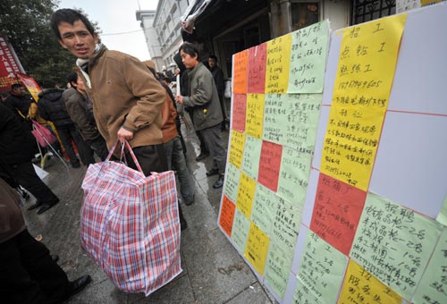 A newly arrived migrant worker in Yiwu, Zhejiang province, checks out recruitment advertisements on Dec 16. Many manufacturing companies in the Yangtze River Delta region are facing labor shortages. Official figures show that in the third quarter of 2010, about 2.11 million laborers were needed in Zhejiang, but only 1.06 million people applied. [Wang Dingchang / Xinhua]    