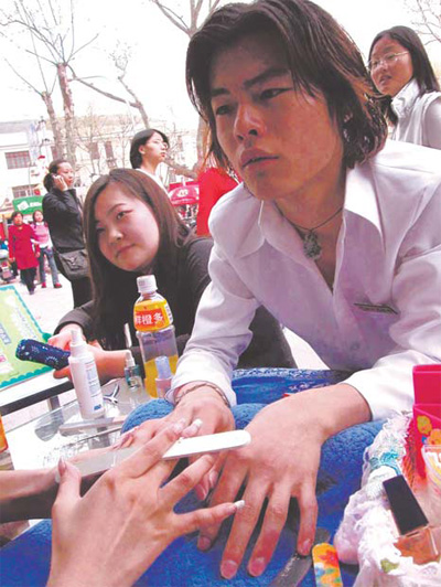 A young man gets his nails polished in downtown Nanjing, capital of Jiangsu province, at a stall set up to promote a beauty salon. Many urban males are spending more time and money on their appearance.