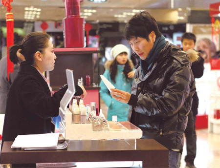 A shopper selects products at a cosmetics counter in Hualian department store in Beijing. Research shows more urban Chinese men are using skincare creams and other beauty products.