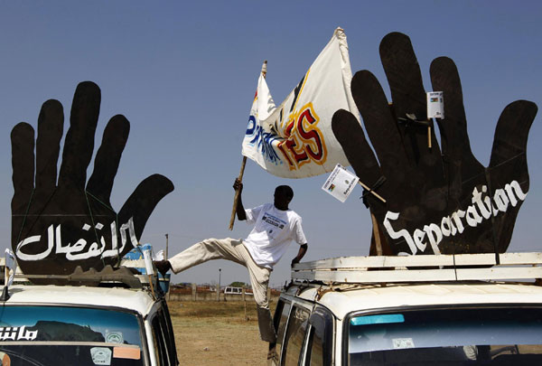 A supporter of the referendum on southern independence adjusts a banner on top of a car during a rally in Juba Jan 5, 2011. [China Daily/Agencies]