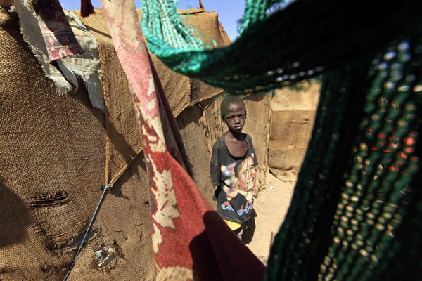 A Southern Sudanese boy in the north stands beside his shelter in an area called Mandela in Khartoum Jan 5, 2011. [China Daily/Agencies]