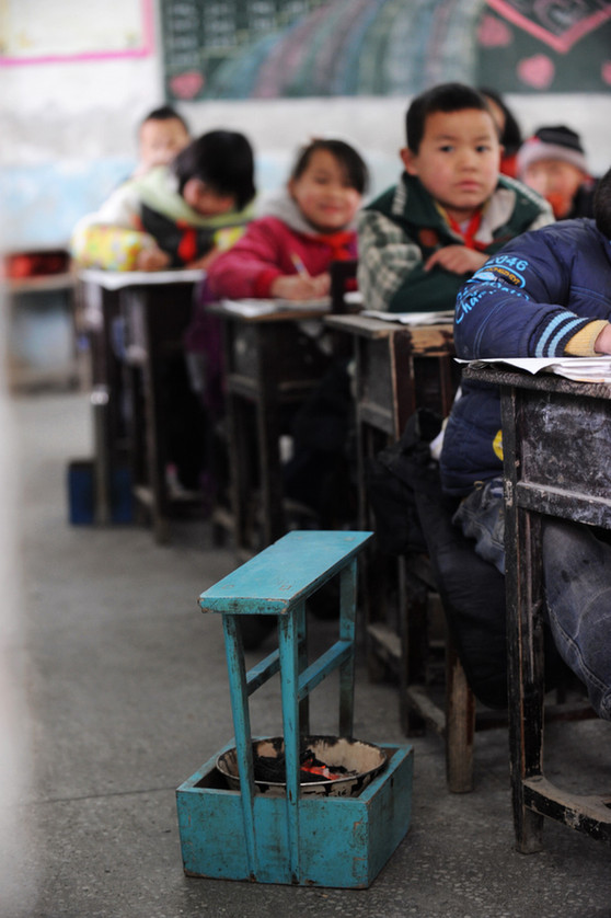 A makeshift hand-stove is placed along a student&apos;s desk at a school in Chaping township, Xinhuang Dong autonomous county in Central China&apos;s Hunan province, Jan 6, 2011. 