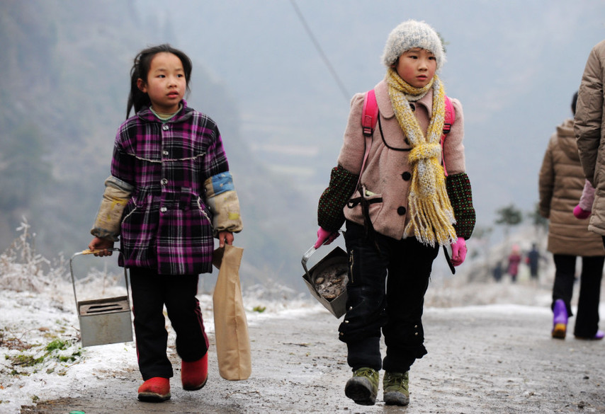 Holding makeshift hand-stoves, students walk to school on an iced mountain road in Xinhuang Dong autonomous county in western-most Hunan province, Jan 6, 2011. [Xinhua]