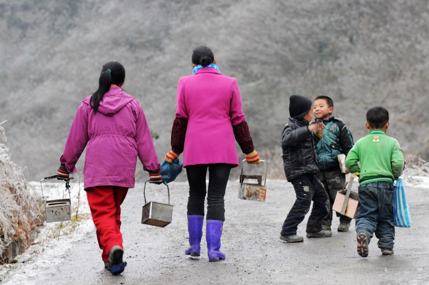 Holding makeshift stoves, students walk on their way home after school on an iced mountain road in Xinhuang Dong autonomous county in western-most Hunan province, Jan 6, 2011. [Xinhua]