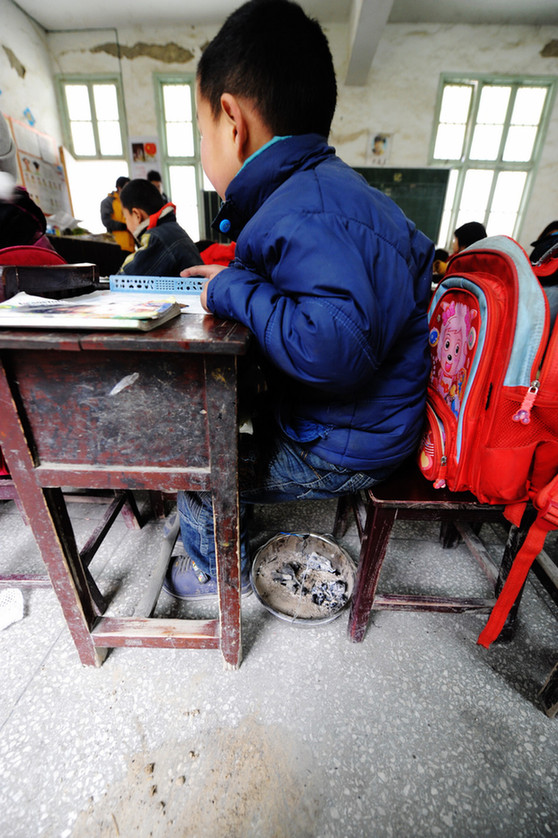 A makeshift hand-stove is placed under a student&apos;s seat at a school in Chaping township, Xinhuang Dong autonomous county in Central China&apos;s Hunan province, Jan 6, 2011. [Xinhua]