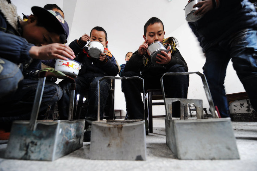 Students dine around their makeshift hand-stoves at a school in Chaping township, Xinhuang Dong autonomous county in Central China&apos;s Hunan province, Jan 6, 2011. [Xinhua]