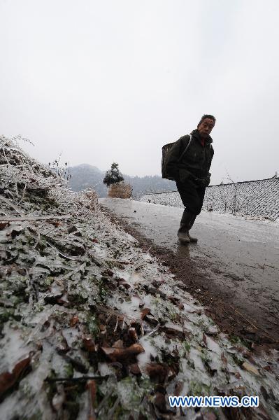 A man walks on the ice-covered road in Xinhuang, central China&apos;s Hunan Province, Jan. 6, 2011. 
