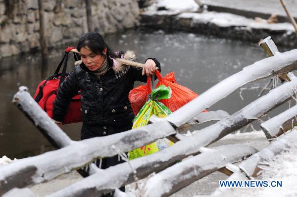 A woman walks on the ice-covered road in Xinhuang, central China&apos;s Hunan Province, Jan. 6, 2011. 