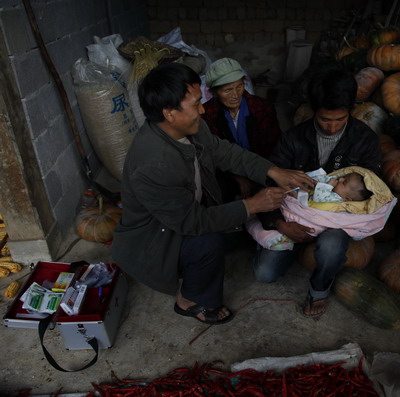 Doctor He Weizhang, of the Bai ethnic group, checks a newborn baby in Ronghua village, Lushui county, Nujiang. 