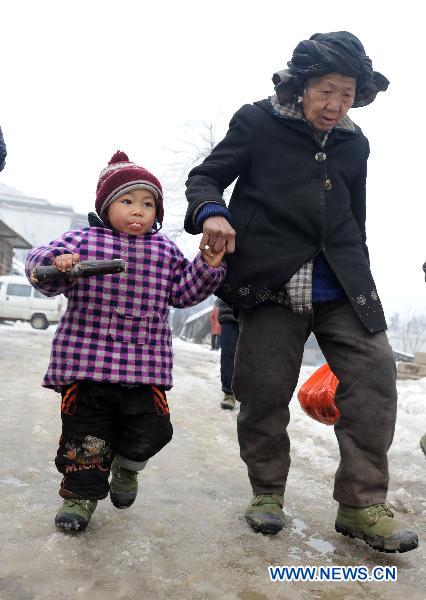 A child (L) eats the sugarcane with an adult at a road covered with snow and ice in a village in Quanzhou County of south China&apos;s Guangxi Zhuang Autonomous Region, Jan. 8, 2010. Despite the difficulty that cold weather brought to local people&apos;s life, children enjoy the fun with the snow-covered world. [Xinhua] 