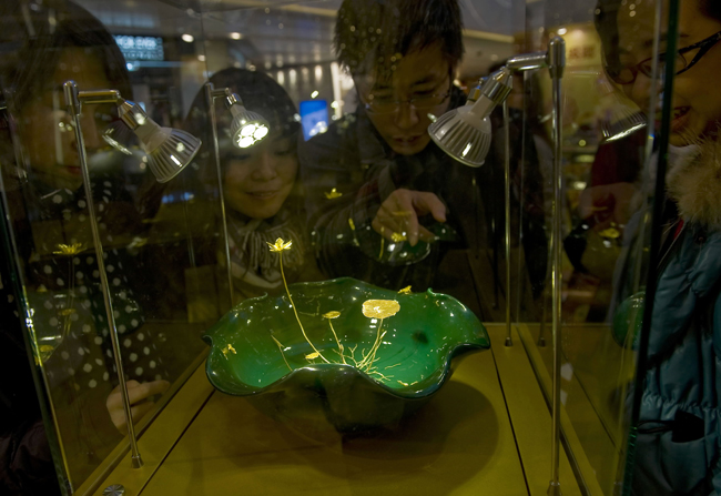 Visitors look at a gold sculpture displayed at an exhibition in Hong Kong, south China, Jan. 10, 2011. A gold sculpture exhibition kicked off here on Monday, with around 100 exhibits worth of 50 million Hong Kong dollars going on show. [Xinhua]