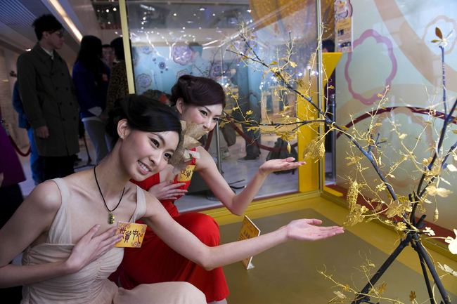 Visitors look at a gold sculpture displayed at an exhibition in Hong Kong, south China, Jan. 10, 2011. A gold sculpture exhibition kicked off here on Monday, with around 100 exhibits worth of 50 million Hong Kong dollars going on show. [Xinhua]