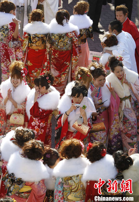 Japanese women in kimonos take pictures during their Coming of Age Day event at an amusement park in Tokyo Jan 10, 2011. [Chinanews.com]