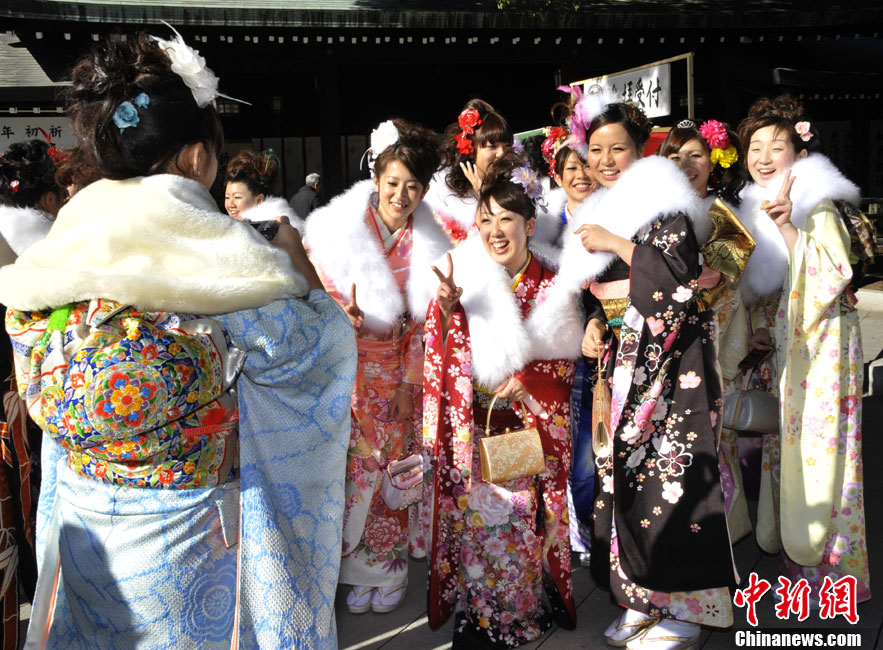 Japanese women in kimonos take pictures during their Coming of Age Day event at an amusement park in Tokyo Jan 10, 2011. [Chinanews.com]