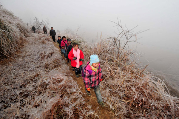 Children escorted by their parents head home on an icy mountain road after school in Dayuan village, Quanzhou county, South China&apos;s Guangxi Zhuang autonomous region, Jan 10, 2011. [Photo/Xinhua]