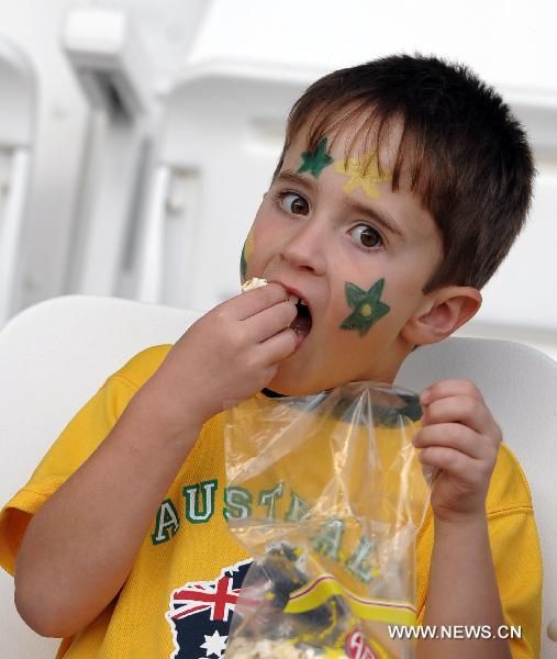 A boy fan of Australia eats popcorn before the Asian Cup group C soccer match between India and Australia in Doha, capital of Qatar, Jan. 10, 2011. [Xinhua] 