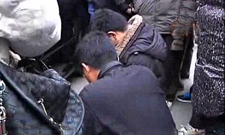 A video grab shows the drivers kneeling with a dead poodle in Suzhou on Jan 9, 2011. [Photo/scol.com] 