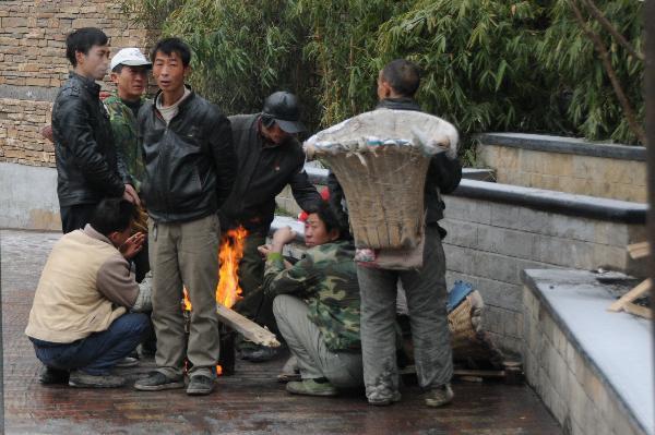 Migrant workers warm themselves by the fire in Guiyang City, capital of southwest China&apos;s Guizhou Province on Jan. 10, 2011. Another wave of freezing rain and sleet and low temperature hit Guizhou Province Monday. Most segments of the inner-provincial highways were affected. At 08:00 of Monday, Jinyang Coach Station, the largest one in the province, suspended the passenger transport services it provided. 