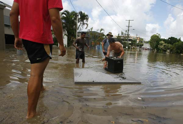 Shopkeepers salvage a coffee machine from their flooded shop in the Brisbane suburb of Milton January 12, 2011. [Xinhua/Reuters] 