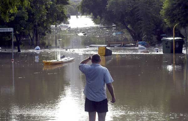 A man looks at debris floating across a flooded street in the inner Brisbane suburb of West End January 12, 2011.
