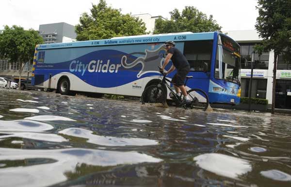 A man cycles through a flooded street in the Brisbane suburb of West End January 12, 2011. 