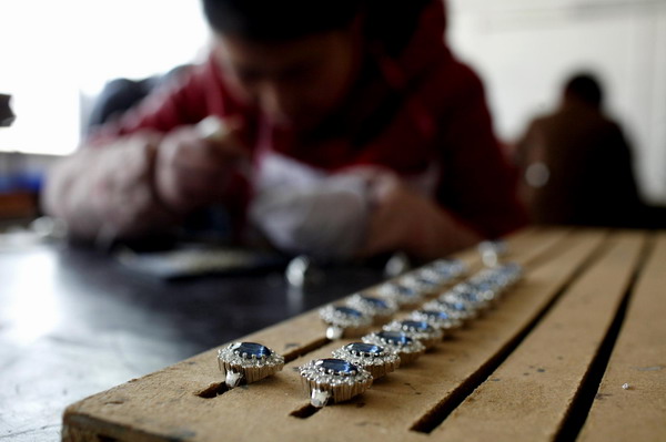 An employee sets stones on a replica of the British royal engagement ring at a jewellery factory in Yiwu, Zhejiang province January 12, 2011. [China Daily/Agencies]