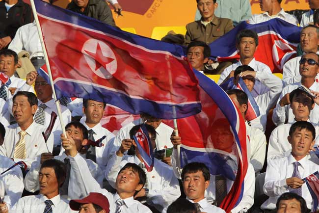 DPRK&apos;s cheering squad wave national flags during their 2011 Asian Cup Group D soccer match against United Arab Emirates at Qatar Sports Club stadium in Doha, Jan 11, 2011. [sina]