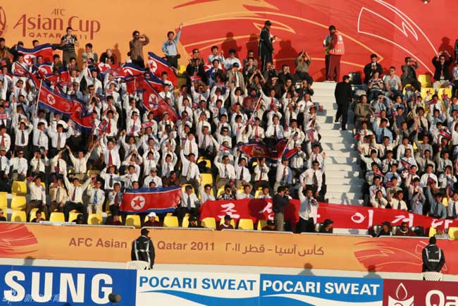 DPRK&apos;s cheering squad wave national flags during their 2011 Asian Cup Group D soccer match against United Arab Emirates at Qatar Sports Club stadium in Doha, Jan 11, 2011. [Photo/sports.sina.com.cn]