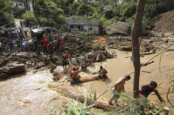 Rescue workers search for victims of a landslide in Teresopolis Jan 12, 2011. Floods and landslides devastated several mountain towns near Rio de Janeiro on Wednesday, killing at least 257 people as torrents of water and mud swept through the region, burying many families as they slept. [China Daily/Agencies]