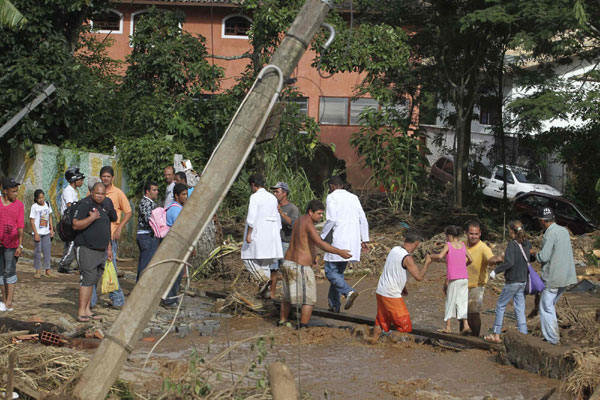 Residents cross a street affected by a landslide in Teresopolis Jan 12, 2011. [China Daily/Agencies]