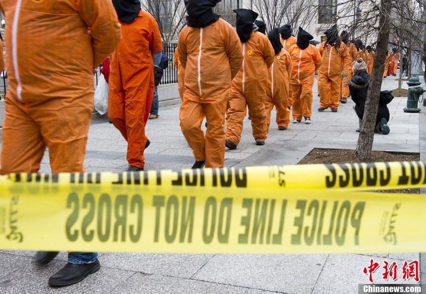 Demonstrators in orange jumpsuits and hoods file in for a rally to &apos;urge President Obama to close the U.S.-controlled detention center in Guantanamo Bay, Cuba on its 9th anniversary&apos; in Washington on January 11, 2011. [CFP]