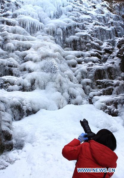 A photographer takes photos of a frozen waterfall in a scenic area of Huangshan City, east China&apos;s Anhui Province, Jan. 12, 2011. As the temperature fell a lot in Huangshan City recently, the rarely-seen frozen waterfall appeared, attracting a lot of tourists and photographers. [Xinhua]