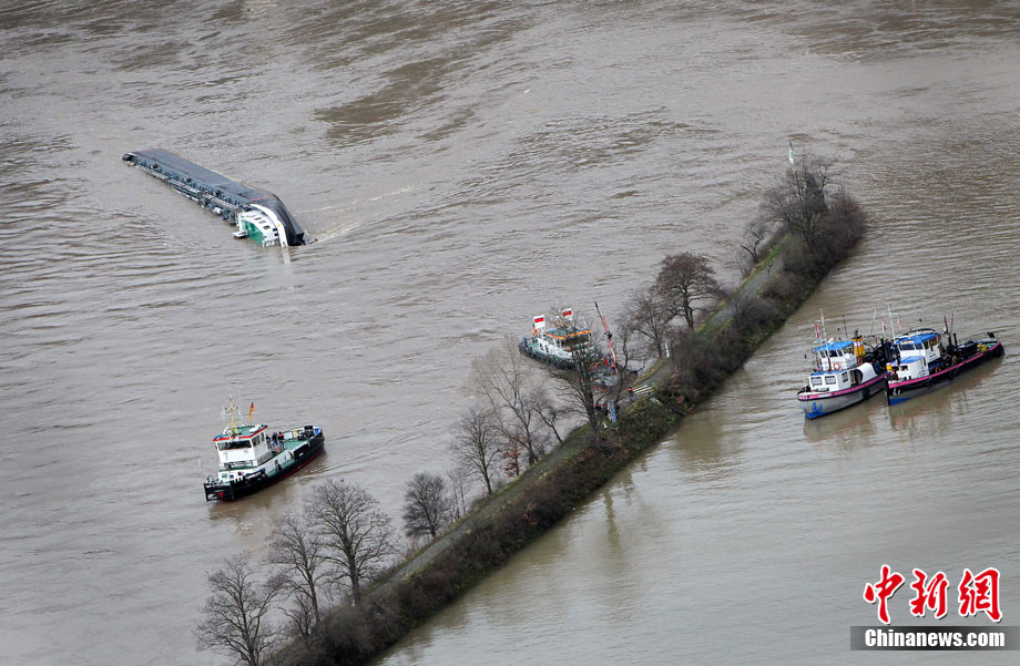 A capsized tanker ship carrying 2,400 tons of sulphuric acid is surrounded by tug boats in the middle of the Rhine (Rhein) river, Europe&apos;s most important shipping way near Sankt Goarshausen January 13, 2011. Two of four crew members were rescued while two others are still being searched for, police said. [photo/Chinanews.com]