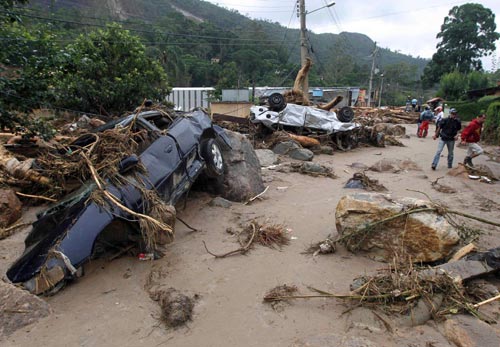 Residents walk past destroyed cars after a landslide in Teresopolis January 13, 2011. [China Daily/Agencies] 