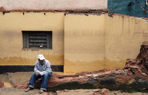 A resident sits on the remnant of a wall of his destroyed house after a landslide in Teresopolis January 13, 2011. [China Daily/Agencies]