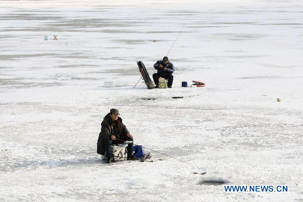 Contestants fish on the iced Waijia River during a fishing contest in Yantai, east China&apos;s Shandong Province, Jan. 12, 2011. More than 50 fishing fans attended the contest on Wednesday. [Xinhua]