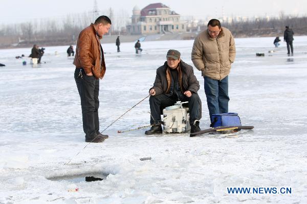 A contestant fishes on the iced Waijia River during a fishing contest in Yantai, east China&apos;s Shandong Province, Jan. 12, 2011. More than 50 fishing fans attended the contest on Wednesday. [Xinhua]