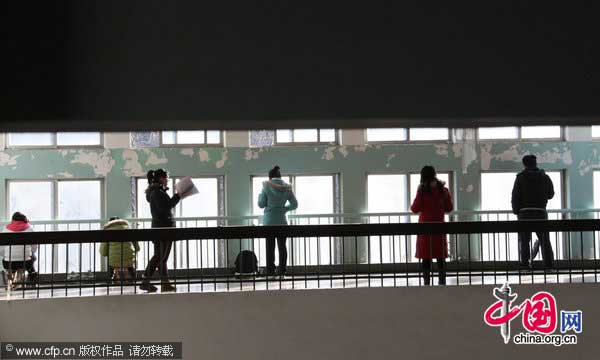 Students who cannot find a seat in the classroom prepare for the exam in a corridor at Shandong Normal University in Jinan, East China&apos;s Shandong province, Jan 13, 2011. [Photo/CFP]