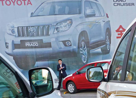 A salesman stands in an empty BYD showroom in Beijing. After Beijing announced plans to restrict vehicle registrations in the capital from Jan 1, many automakers are looking at China's second- and third-tier cities. 