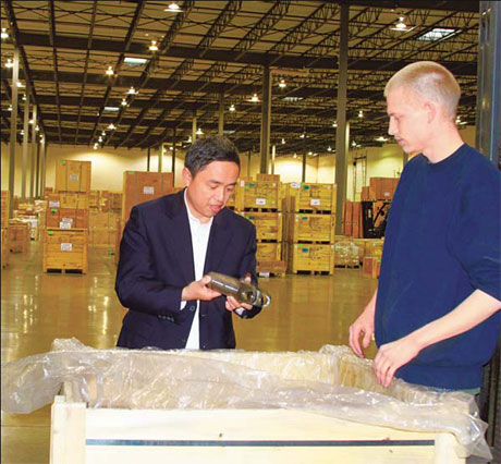 Wanxiang America President Ni Pin and a US staff member checking an auto part just shipped in from China at the company's warehouse in Elgin, Illinois. [China Daily]