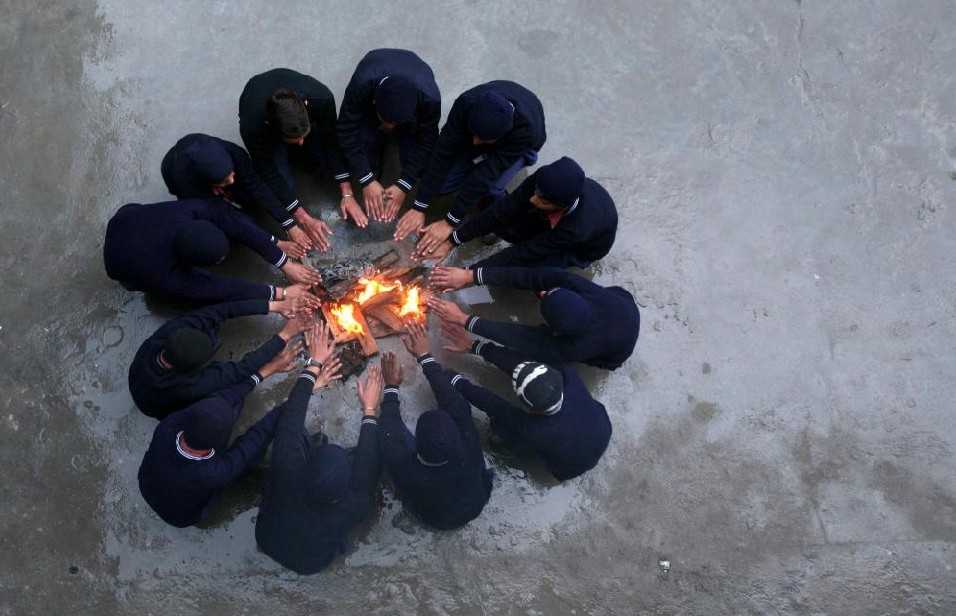 School children sit around a fire to warm themselves up during their recess break inside a school on a cold day in Jammu January 14, 2011.[[China Daily/Agemcies]